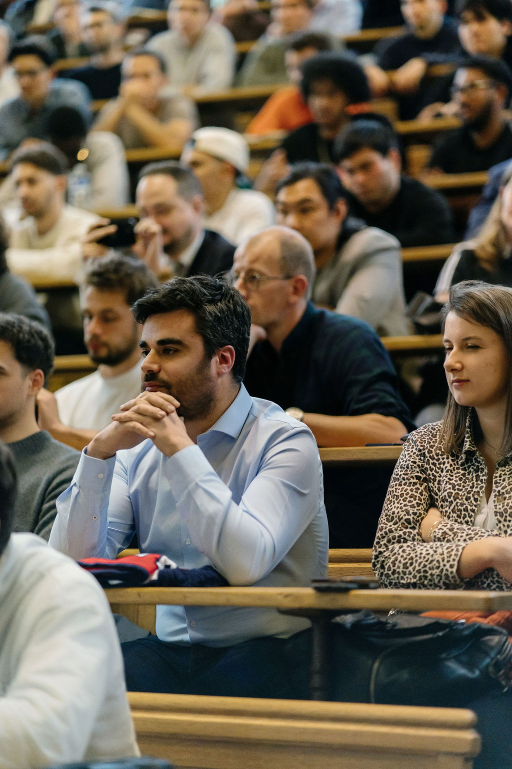 Un spectateur écoute la conférence, assis dans les bancs de bois